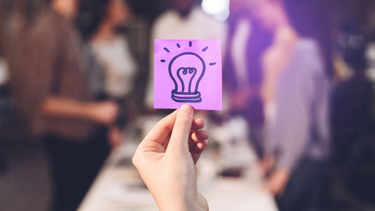 Mão segurando um desenho de lâmpada